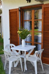 a white table with four chairs and a vase with flowers at Eretria Park Studios in Eretria