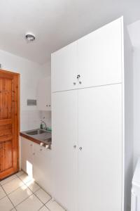 uma cozinha com armários brancos e um lavatório em Eretria Park Studios em Erétria