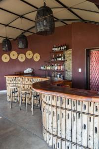 un bar en un restaurante con mesas y taburetes de madera en Serondela Lodge en Mbalastinte
