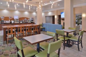 a restaurant with tables and chairs and a bar at Holiday Inn Express & Suites Dearborn SW - Detroit Area, an IHG Hotel in Dearborn