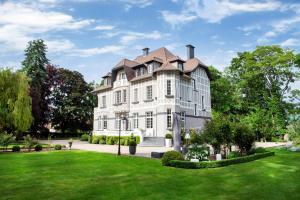 ein großes weißes Haus mit grünem Rasen in der Unterkunft Le Château de Fresnoy en Gohelle in Fresnoy-en-Gohelle