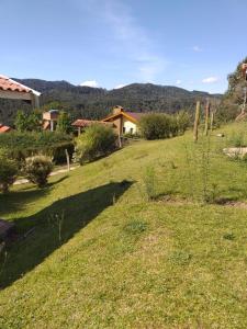 un champ d'herbe avec une maison en arrière-plan dans l'établissement Um lugar para curtir, descansar e amar!, à Campos do Jordão