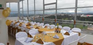 Cette chambre comprend des tables, des chaises blanches et des fenêtres. dans l'établissement Hotel Hangas Mayo, à Ipiales