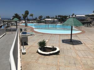 a swimming pool with an umbrella and a resort at Bungalow Einstein in Maspalomas