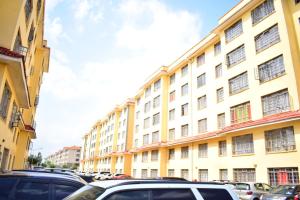 a large yellow building with cars parked in a parking lot at Great house BnB near jkia in Nairobi