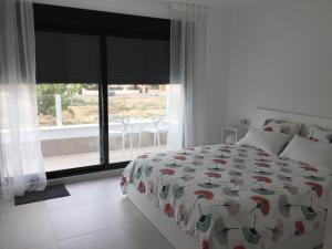 a white bedroom with a bed and a large window at Casa Ribalta in San Pedro del Pinatar