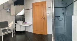 a bathroom with a shower and a wooden door at Ferienwohnung Hochwaldblick 2 in Morbach +3 photos
