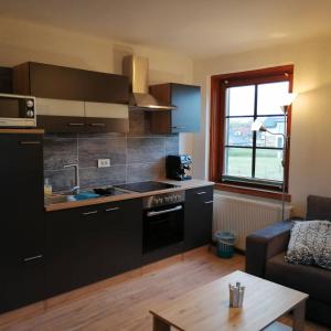 a kitchen with black cabinets and a table and a couch at Parkweg Lodge in Faak am See