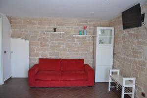 a red couch in a room with a brick wall at La persiana sul mare in Giovinazzo