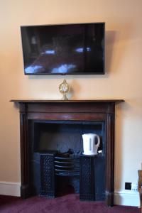 a tv above a fireplace with a coffee cup on it at The Red Lion in Llangadog
