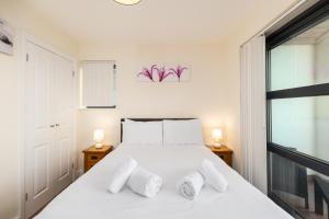 a bedroom with a white bed with two lamps at West Beach - Holiday Apartments in Westward Ho
