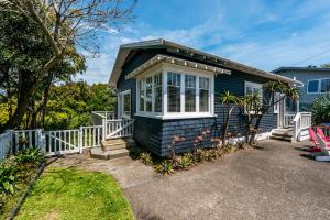 a small blue house with a white fence at Mrs Jones Holiday Cottage - Waiheke Holiday Home in Oneroa