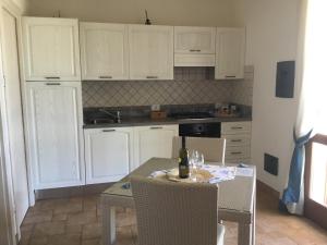 a kitchen with white cabinets and a table with a bottle of wine at Borgo della Luna in Birgi Vecchi
