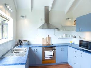 a kitchen with white cabinets and blue counter tops at Two Rooms Onetangi - Onetangi Holiday Home in Onetangi