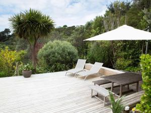 a wooden deck with a table and chairs and an umbrella at Two Rooms Onetangi - Onetangi Holiday Home in Onetangi