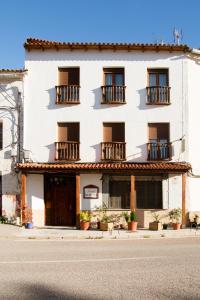 a white building with balconies on a street at Hostal La Toba in Cañete