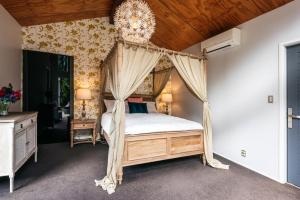 a bedroom with a canopy bed and a chandelier at Kereru - Waiheke Holiday Home in Ostend