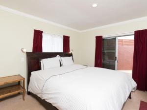 a bedroom with a large bed with red curtains at Captain's Quarters - Opua Holiday Home in Opua