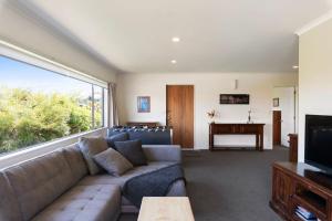 a living room with a couch and a television at Sun on Seaview - Paraparaumu Beach Holiday Home in Paraparaumu Beach