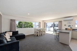 Sun on Seaview - Paraparaumu Beach Holiday Home في باراباراومو بيتش: غرفة معيشة مع أريكة وطاولة