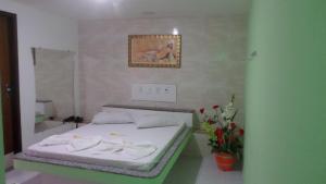 1 dormitorio con 1 cama, espejo y flores en Hotel Lotus, en Salvador
