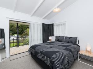 een slaapkamer met een zwart-wit bed en een balkon bij Paihia Centre Peace - Central Paihia Holiday Home in Paihia