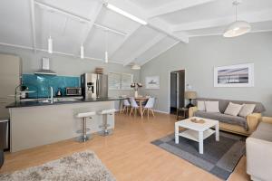 a kitchen and living room with a couch and a table at Pohutukawa Breeze - Papamoa Beach Holiday Home in Papamoa