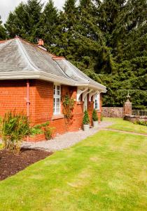 una casa de ladrillo rojo con un patio de hierba en The Gardener's Cottage en Dunblane