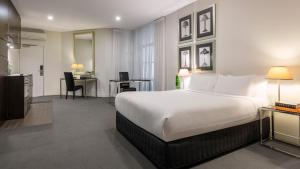 a hotel room with a large bed and a desk at Oaks Melbourne on Collins Suites in Melbourne