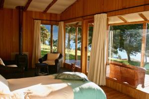 a bedroom with a bed and a large window at Lodge El Mirador De Guadal in Puerto Guadal