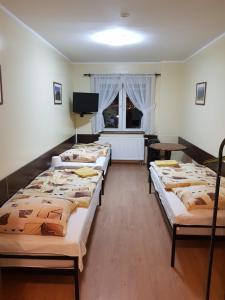 a row of beds in a room with a tv at Pokoje Relaks 2 in Gdynia