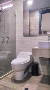 uma casa de banho com um WC, um lavatório e um espelho. em Hotel WLH Bogota - White Lighthouse em Bogotá
