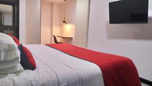 1 dormitorio con 1 cama con manta roja y blanca en Hotel WLH Bogota - White Lighthouse, en Bogotá