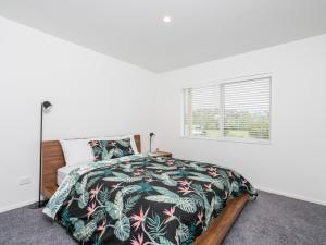 a bedroom with a bed with a black and green blanket at Ruakaka Sands - Ruakaka Holiday Home in Ruakaka
