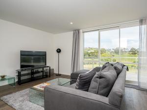 a living room with a couch and a large window at Ruakaka Sands - Ruakaka Holiday Home in Ruakaka