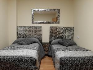 a room with two beds and a mirror on the wall at Arroyo in Coreses