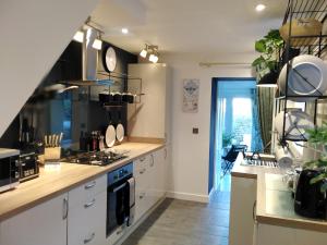 a kitchen with white cabinets and a stove top oven at Aubrey Cottage in Cowbridge