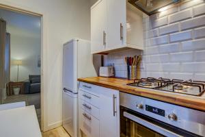 uma cozinha com armários brancos e um forno com placa de fogão em Garden Gate Upper Apartment em Prestwick