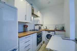 a kitchen with white cabinets and a washer and dryer at Garden Gate Upper Apartment in Prestwick
