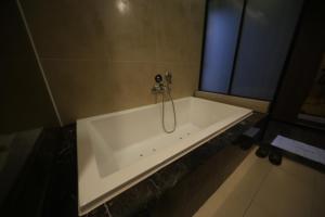 a bath tub with a shower in a bathroom at Beomil Brown Dot Hotel in Busan