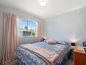 Schlafzimmer mit einem Bett und einem Fenster in der Unterkunft Central Riverside Retreat - Taupo Holiday Home in Taupo