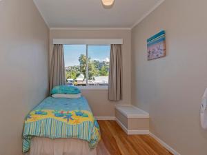 a small bedroom with a bed and a window at Town Centre Treat - Tairua Holiday Home in Tairua