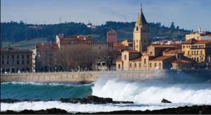 una città con edifici e onde in acqua di Apto. Vista Playa Poniente a Gijón