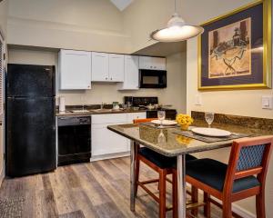 a kitchen with a black refrigerator and a table with chairs at Chase Suite Hotel Rocky Point Tampa in Tampa
