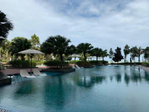 a large swimming pool with chairs and palm trees at Deluxe Holiday Studio Suite at Timurbay with Seaview in Kampung Sungai Karang