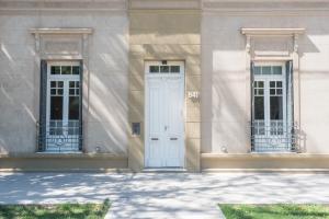 a white building with two windows and a door at La Casona Apart Boutique in Marcos Juárez