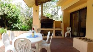 un patio con sillas blancas, mesa y chimenea en Chalet Utama en Punta del Este