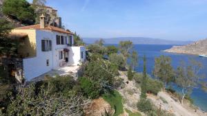 a white house on a hill next to the water at Arbeli house in Mandraki