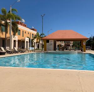 a swimming pool with a gazebo next to a building at Mar Azul Bay View Apartment in Boqueron