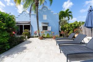 a blue house with chairs and palm trees at Sandy Lodge, 4 Porters Court in Saint James